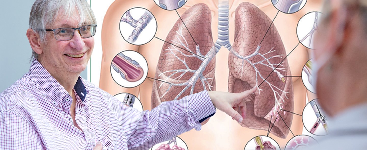 MHH-Pneumologe Professor Dr. Tobias Welte zeigt mit dem Zeigefinger auf eine große Grafik mit einer menschlichen Lunge.