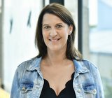 Porträtbild von Verena Mehr, die eine hellblaue Jeansjacke und darunter ein dunkelfarbiges Oberteil trägt. 