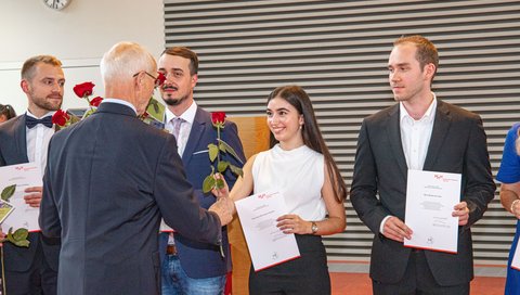 Alumni-Vorsitzender Prof. Dr. Piepenbrock übergibt eine rote Rose des Ehemaligenvereins an die Alumnis