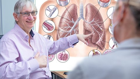 Professor Dr. Tobias Welte sitzt vor einem Bildschirm, auf dem eine Grafik eines gesunden und eines COPD-geschädigten Lungenflügels zu sehen ist.