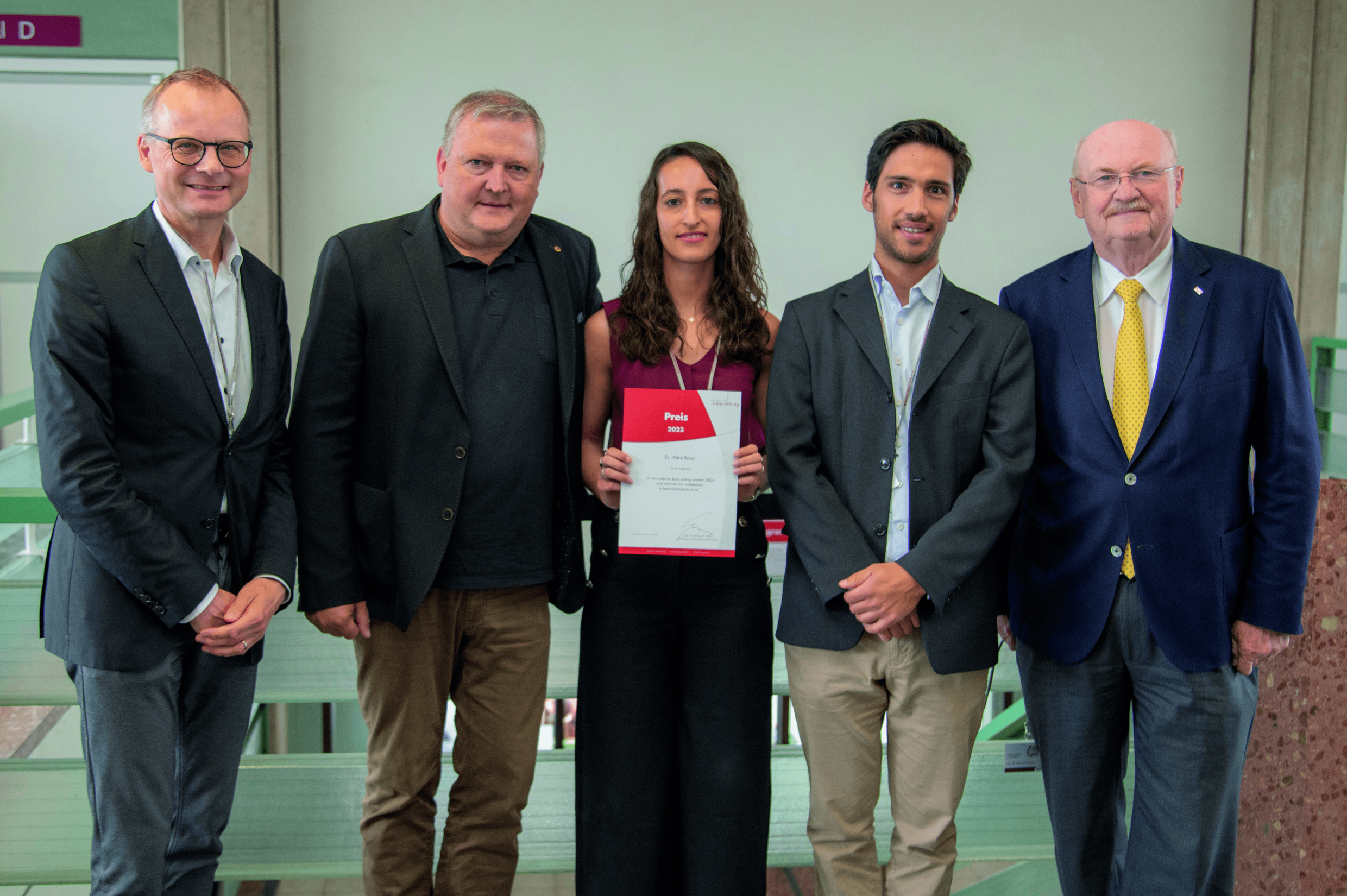 Professor Dr. Heiner Wedemeyer, Professor Dr. Michael Ott, Dr. Alice Rovai, Dr. Dr. Simon Krooss und MHH-Präsident Professor Dr. Michael Manns stehen nebeneinander. Frau Dr. Rovai hält eine Urkunde in den Händen