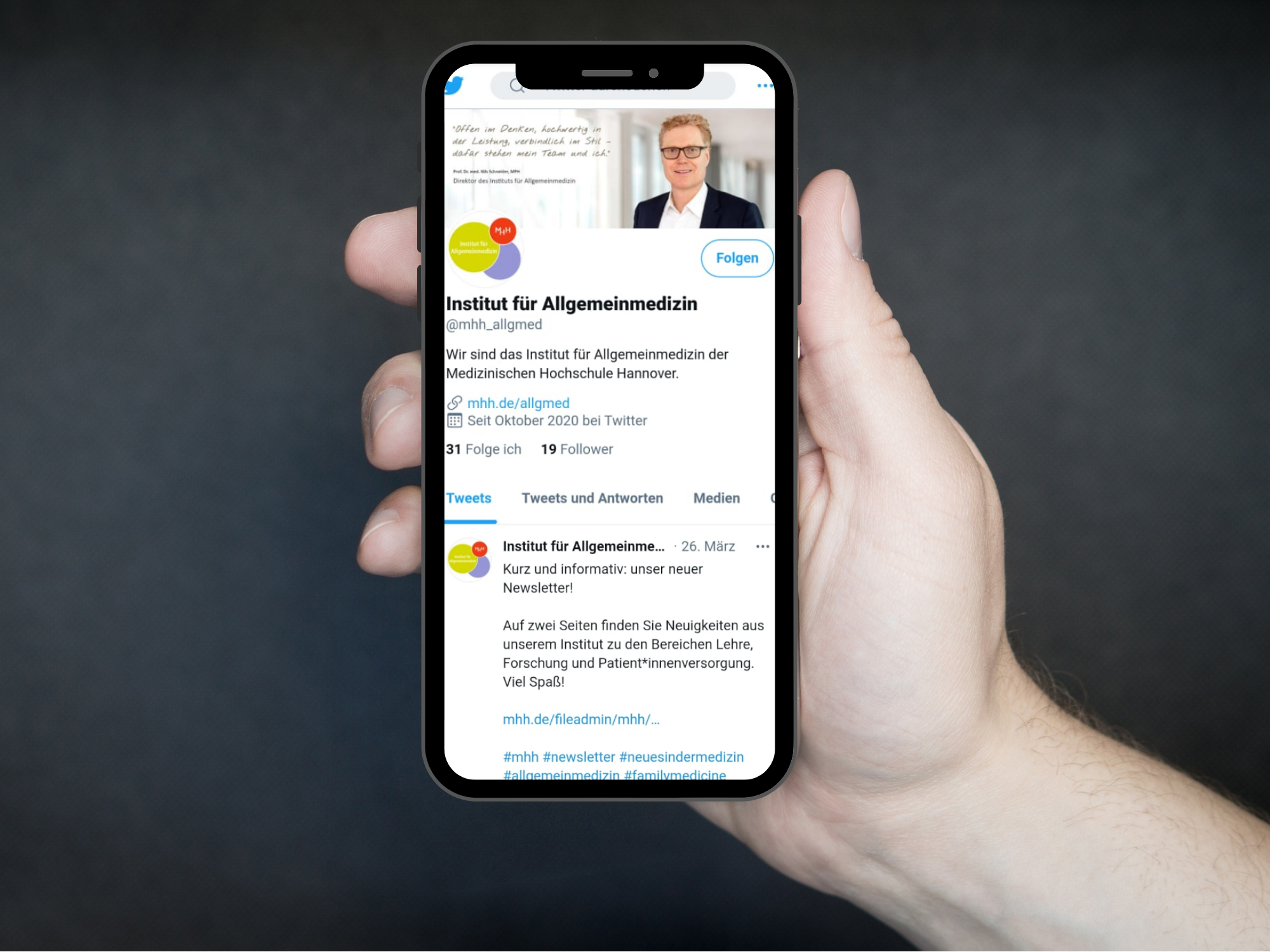 Eine Hand hält ein Smartphone. Auf dem Smartphone ist die Twitter-Startseite des Instituts für Allgemeinmedizin und Palliativmedizin zu sehen.