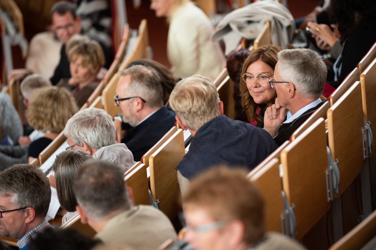 Blick in de Stuhlreihen des Hörsaals, in denen fast jeder Platz besetzt ist.