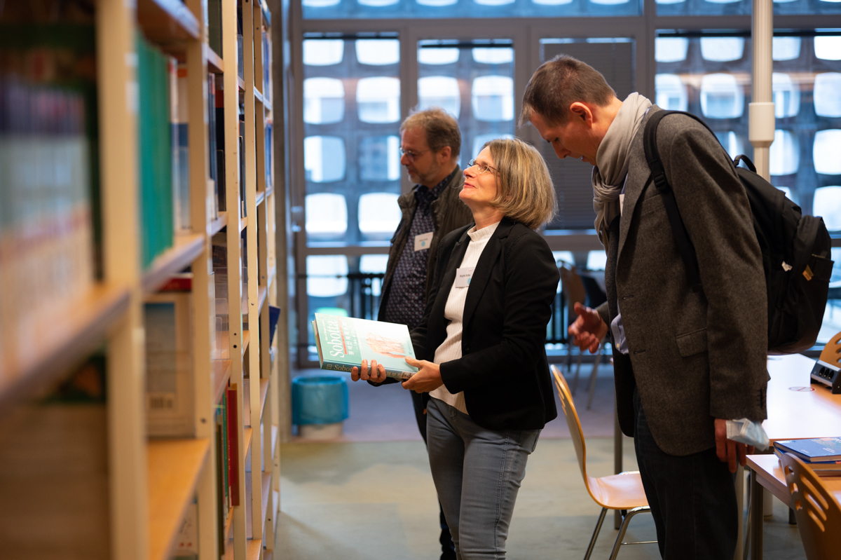 Ein Mann und eine Frau stehen vor einem Bücherregal und unterhalten sich.