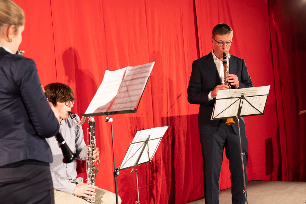 Ein Klarinettentrio musiziert auf der Bühne vor rotem Vorhang.