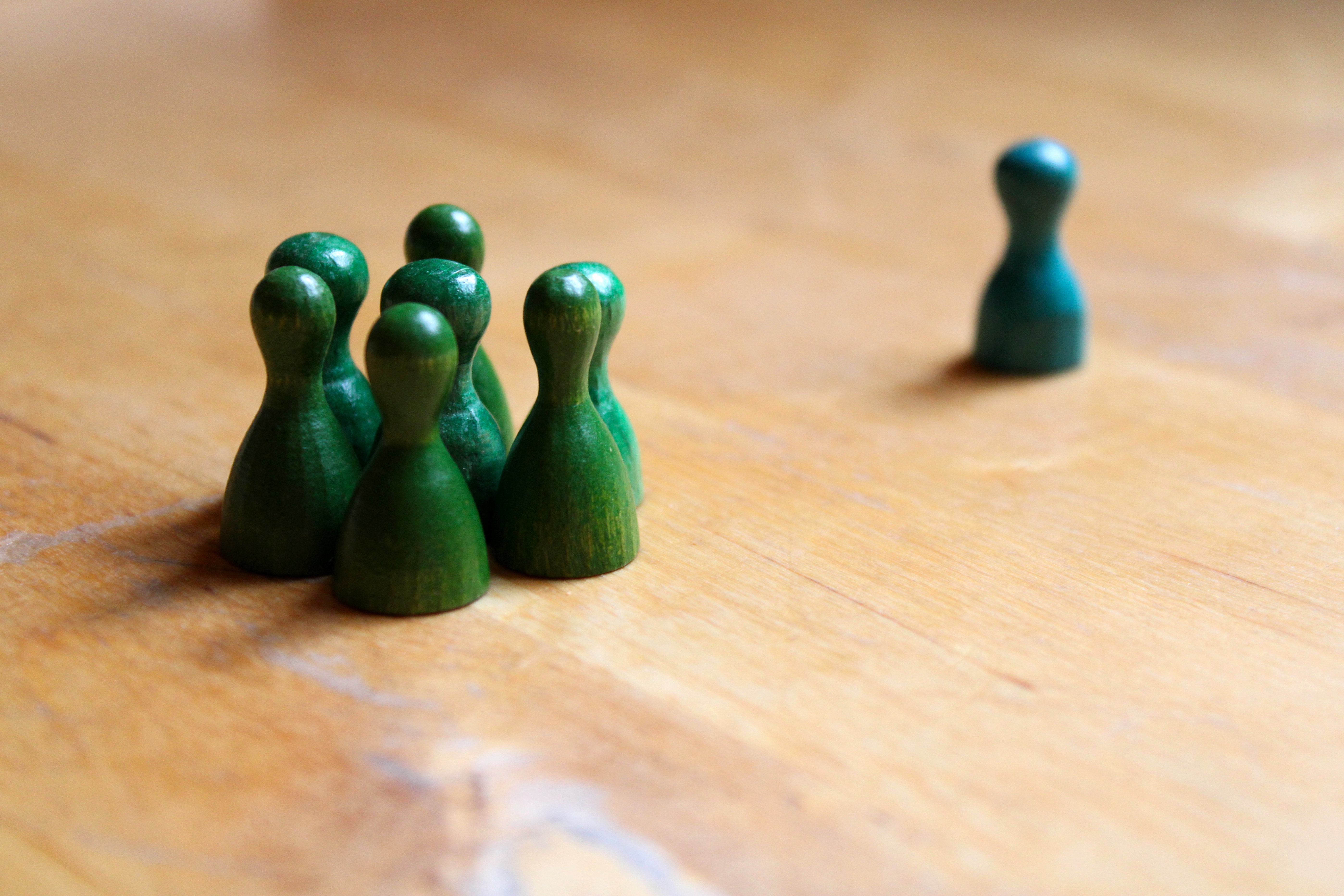 grüne Spielfiguren, Isolation grüne Spielfiguren zusammenstehend als Gruppe, eine Spielfigur einzeln isoliert