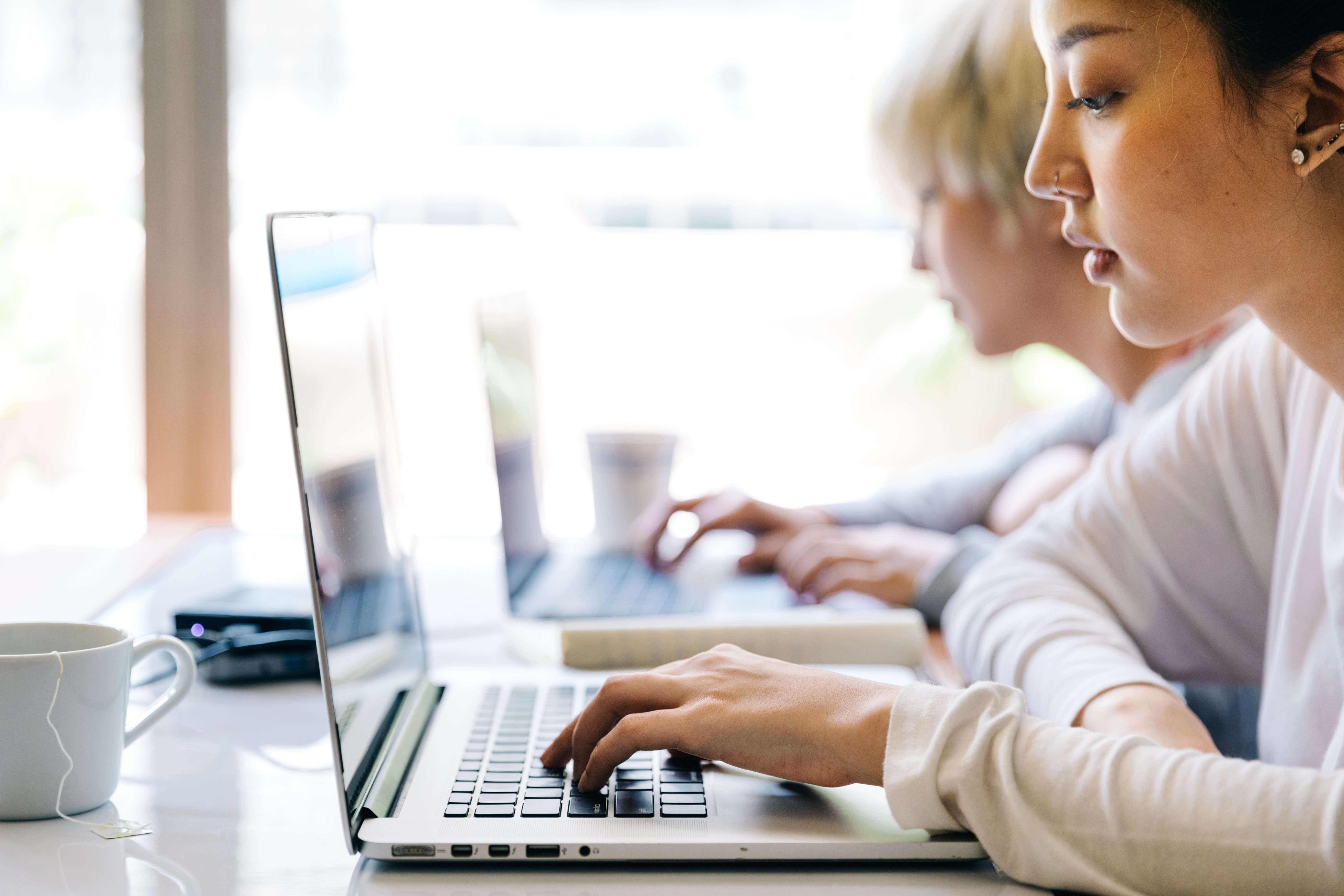 Das Bild zeigt zwei Personen, die an ihren Laptops arbeiten.