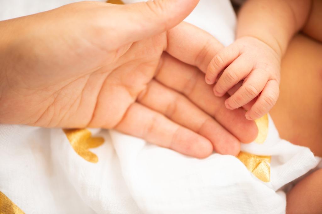 Eine Hand eines Babys das die seiner Mama umfasst.