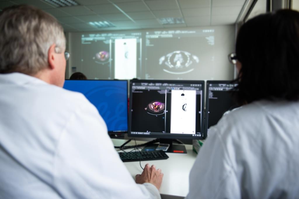 Zwei Ärzte von hinten die sich auf einem Bildschirm in einer Tumorkonferenz radiologische Bildern ansehen.