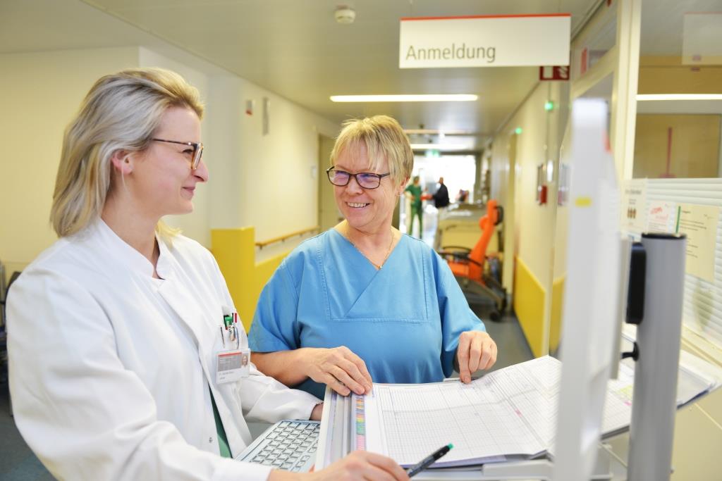 Eine Ärztin und eine onkologische Pflegekraft stehen auf der Station zusammen und besprechen sich.