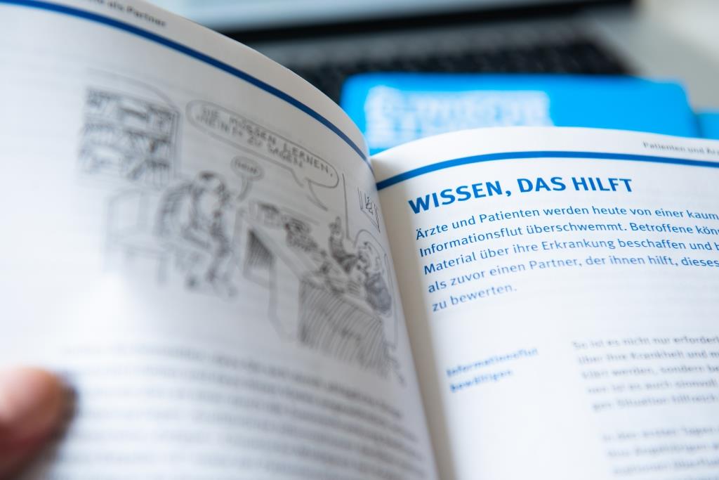 Eine aufgeschlagenes Heft der Blauen Ratgeber der Deutschen Krebshilfe in dem steht "Wissen, das hilft".