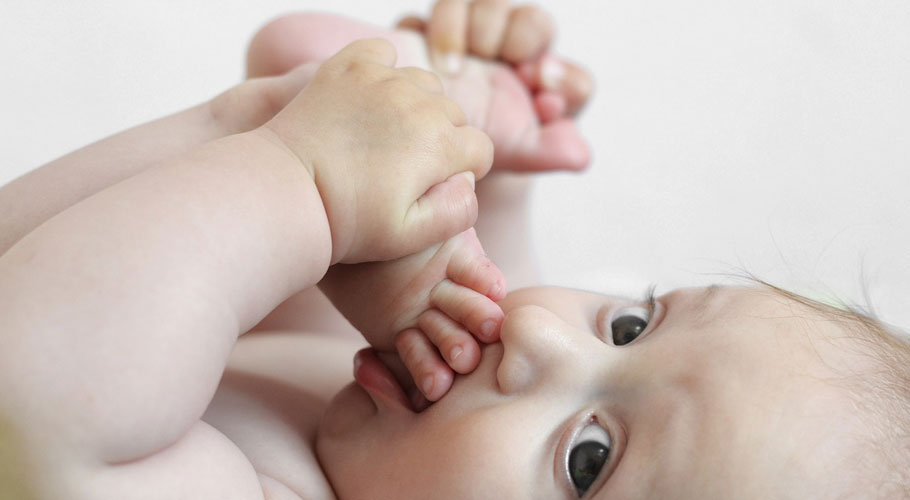 Baby hölt Füße und Hände zum Gesicht herangezogen