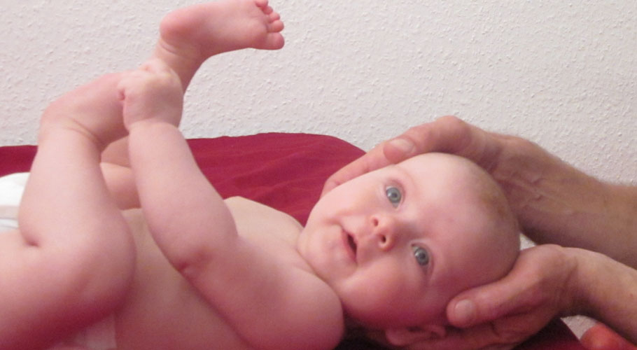 Ostheopat hält Kopf eines Babys in seinen Händen