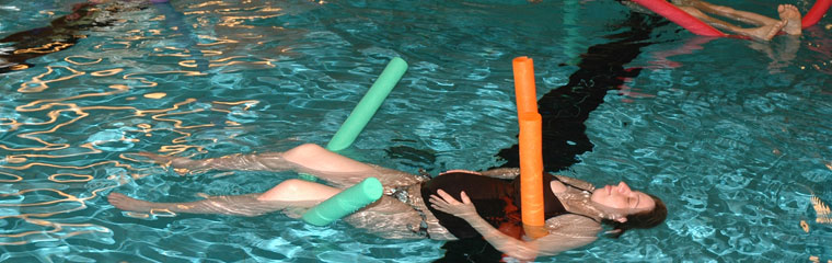 Schwangere lößt sich auf zwei "Schwimmnudeln" im Schwimmbecken treiben