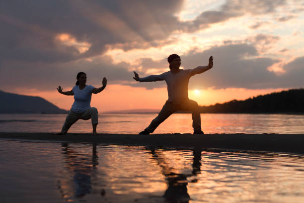 Frau und Mann beim Qigong im Wasser bei Sonnenuntergang