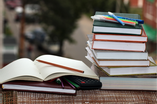 aufgeschlagenes Buch neben Bücherstapel