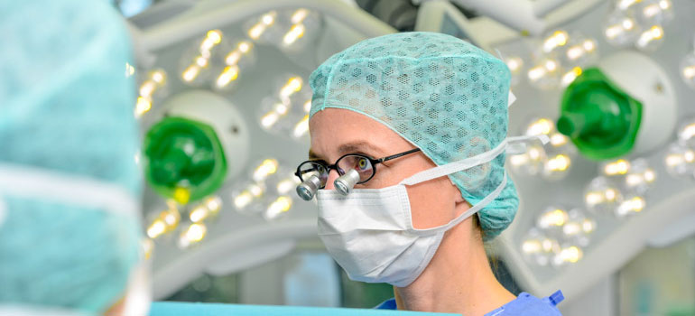 Dr. Mareike Leffler im OP Saal in OP Kleidung. Sie trägt eine Mikroskopbrille.