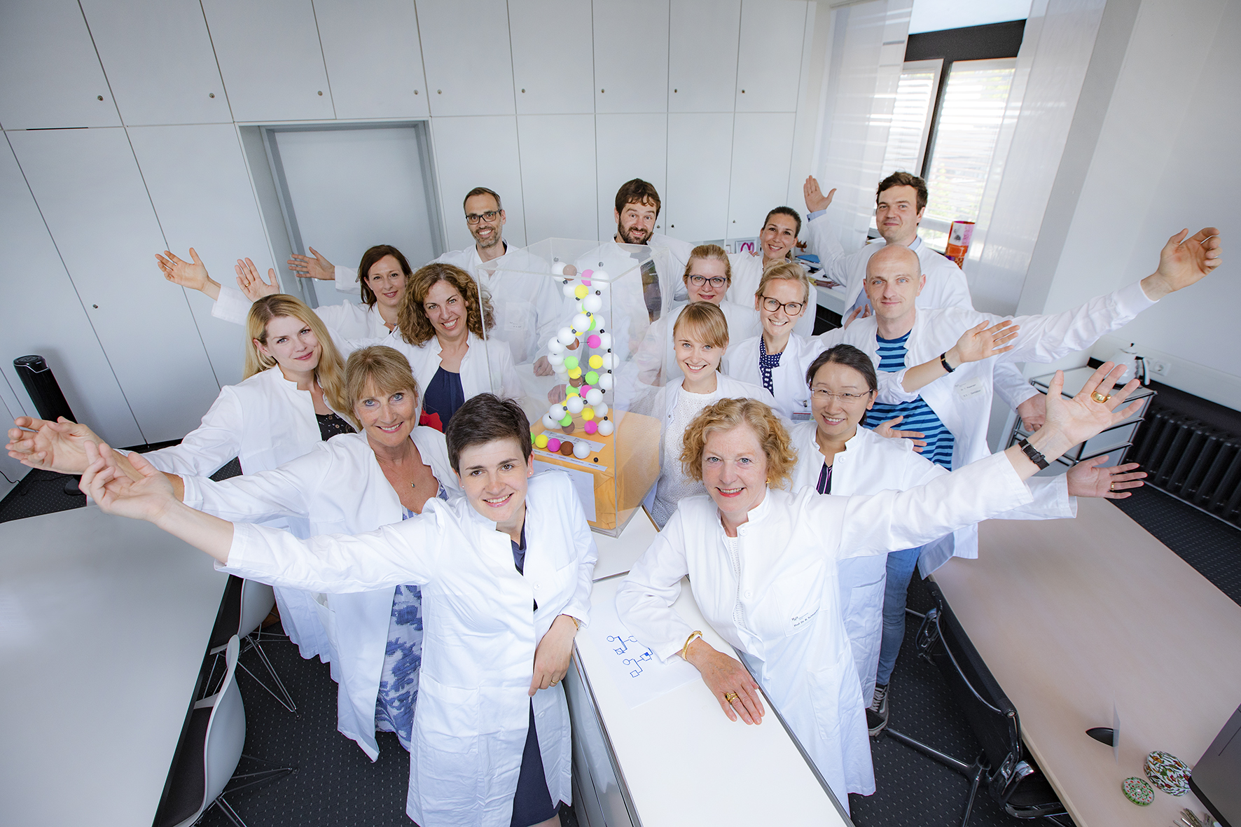 Team of doctors consisting of specialists and doctors in training with their hands in the air.