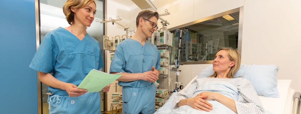 Prof. Vogt steht mit einer Krankenschwester am Patientenbett und erklärt den Befund.
