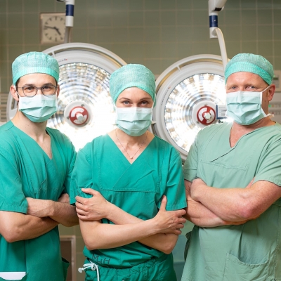 drei Chirurgen in OP-Kleidung mit verschränkten Armen