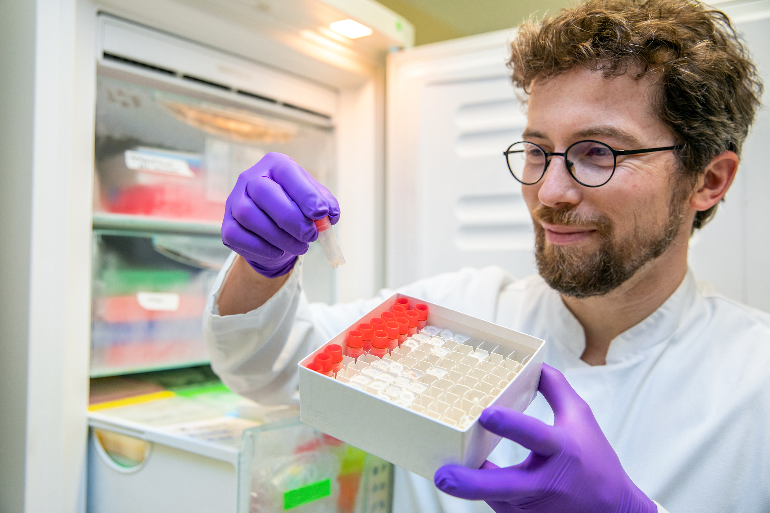 Dr. Richard Taubert steht mit Blutserum-Proben aus den Antikörperstudien zur Autoimmunhepatitis am Kühlschrank; Copyright: Karin Kaiser / MHH.