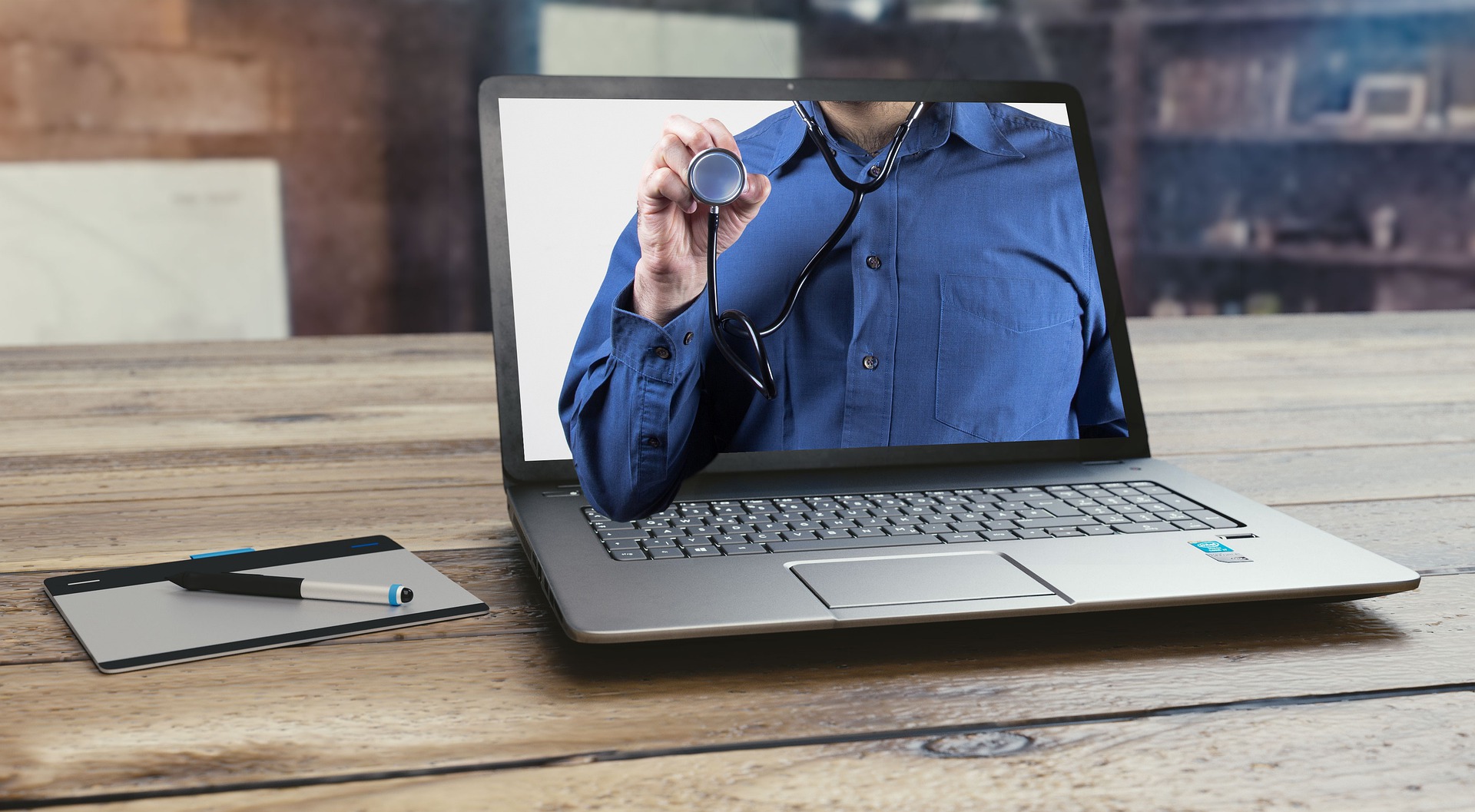Ein Laptop, auf dessen Bildschirm ein Arzt mit Stethoskop zu sehen ist.