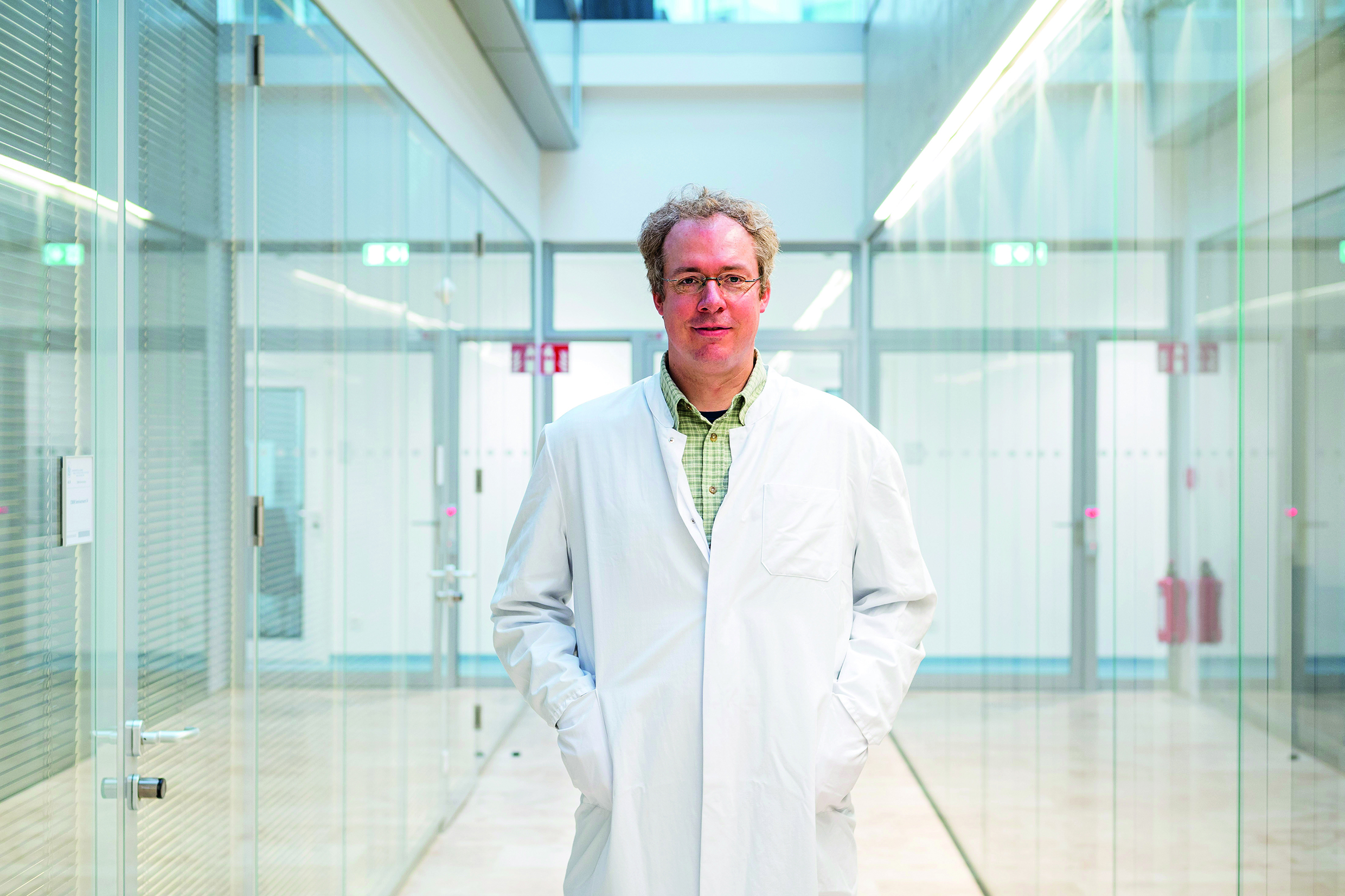 Der Herpesvirus-Forscher Professor Dr. Thomas Krey steht in einem Gang der Universität Lübeck.