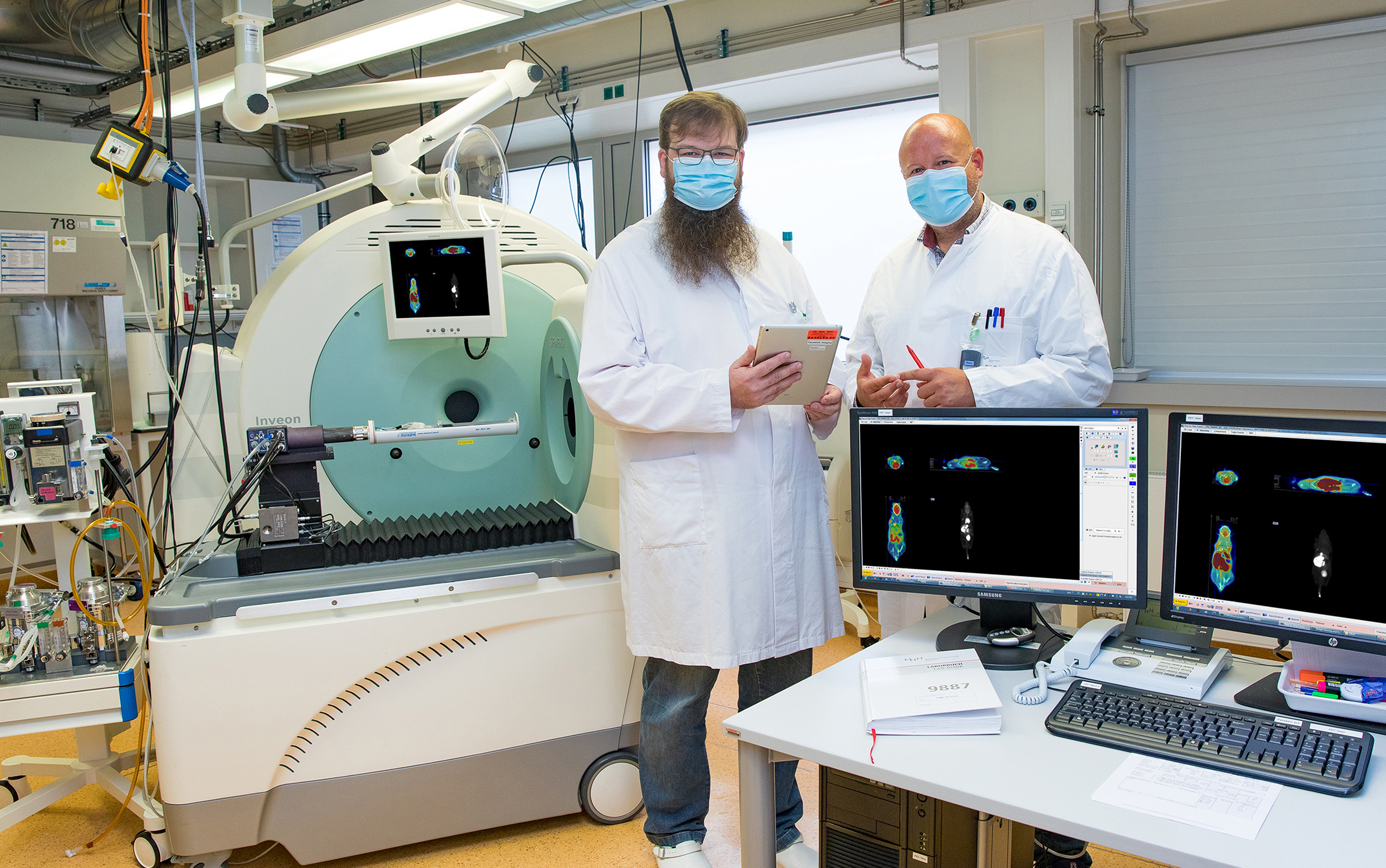 Dr. Jens Bankstahl und Professor Dr. Tobias Ross stehen neben einem Kombinationsgerät für präklinische Positronenemissionstomographie/Computertomographie (PET/CT)