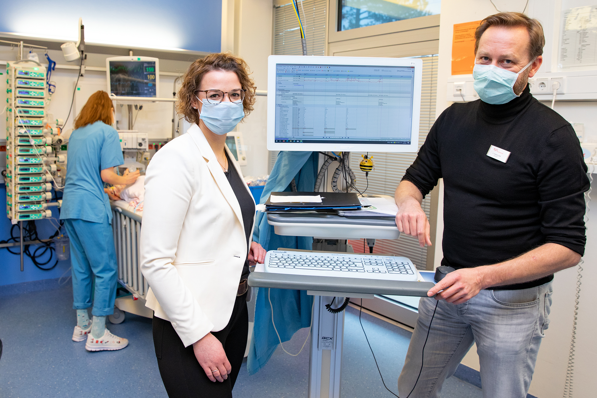 Dr. Antje Wulff und Dr. Thomas Jack stehen neben einem PDMS-Monitor auf der Kinderintensivstation