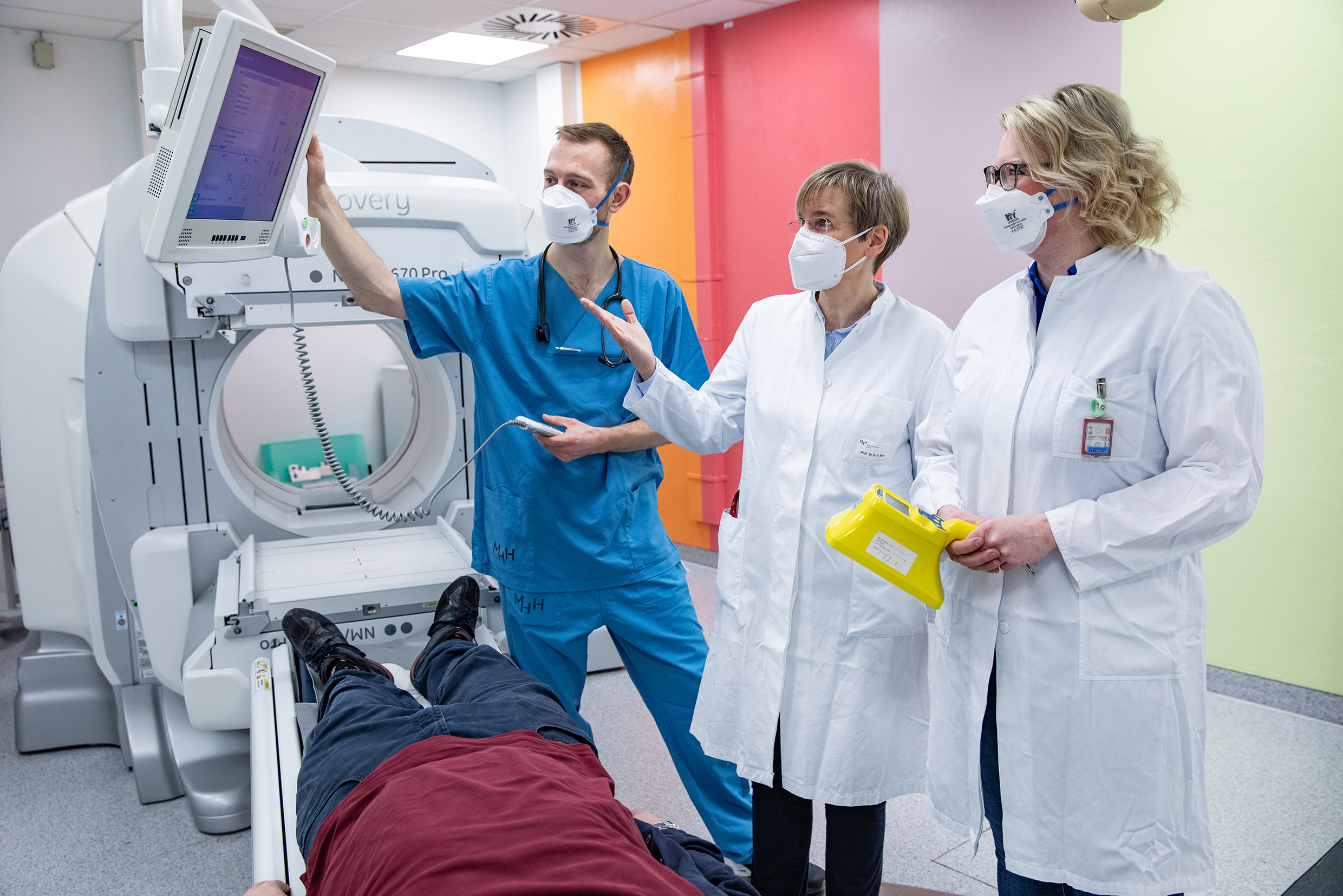 Professor Dr. Dr. Anette Melk stands with PRACTIS participants Dr. Johanna Diekmann and Dr. Carl Grabitz during an examination situation in MHH nuclear medicine at a special imaging device.