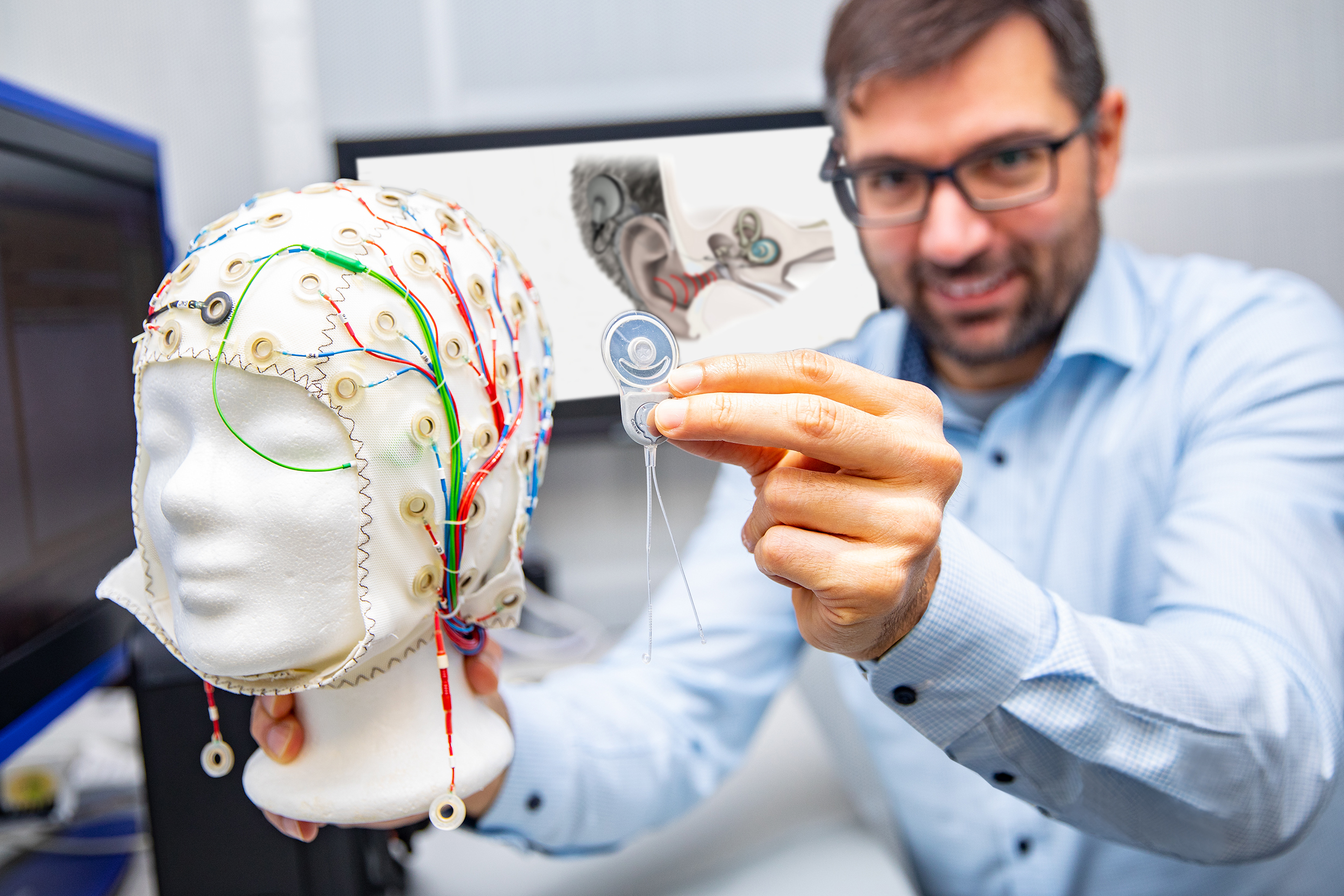 Professor Dr Waldo Nogueira Vazquez holds a cochlear implant to an EEG cap to measure the signals during auditory processing in the brain