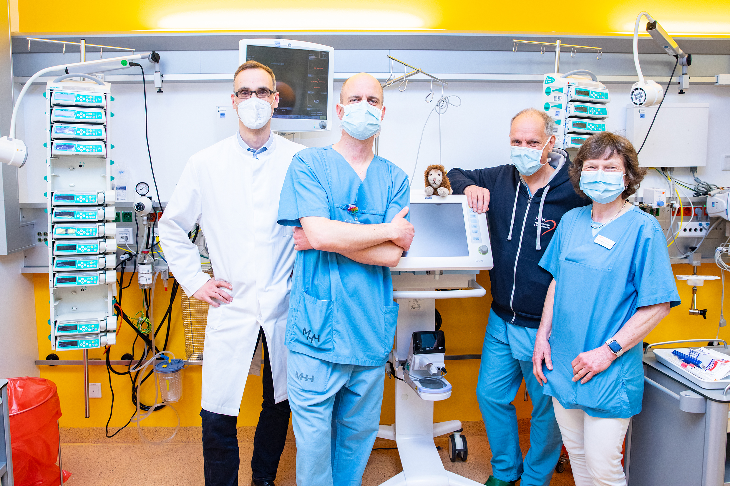 Dr. Bernd Auber, Dr. Alexander von Gise und Dr. Michael Sasse von der intensivmedizinischen Station sowie Professorin Dr. Bettina Bohnhorst von der neonatologischen Station stehen in einem Patientenzimmer der Kinderklinik. 