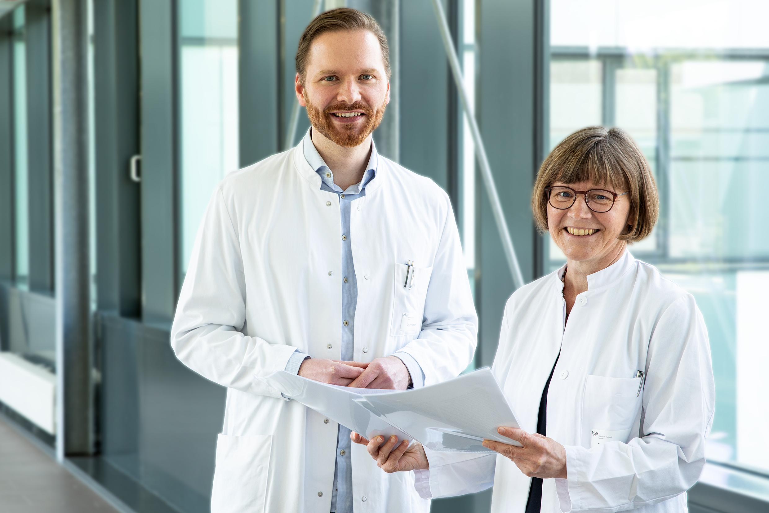 Auf dem Foto sind Dr. Hümmert und Professorin Trebst, in einem Gang der MHH stehend, zu sehen. 