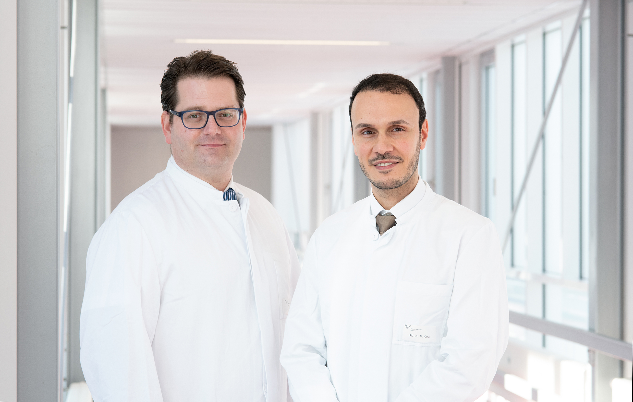 PD Dr. Philipp Ivanyi and Prof. Dr. Mohamed Omar standing in a hallway at Hannover Medical School.