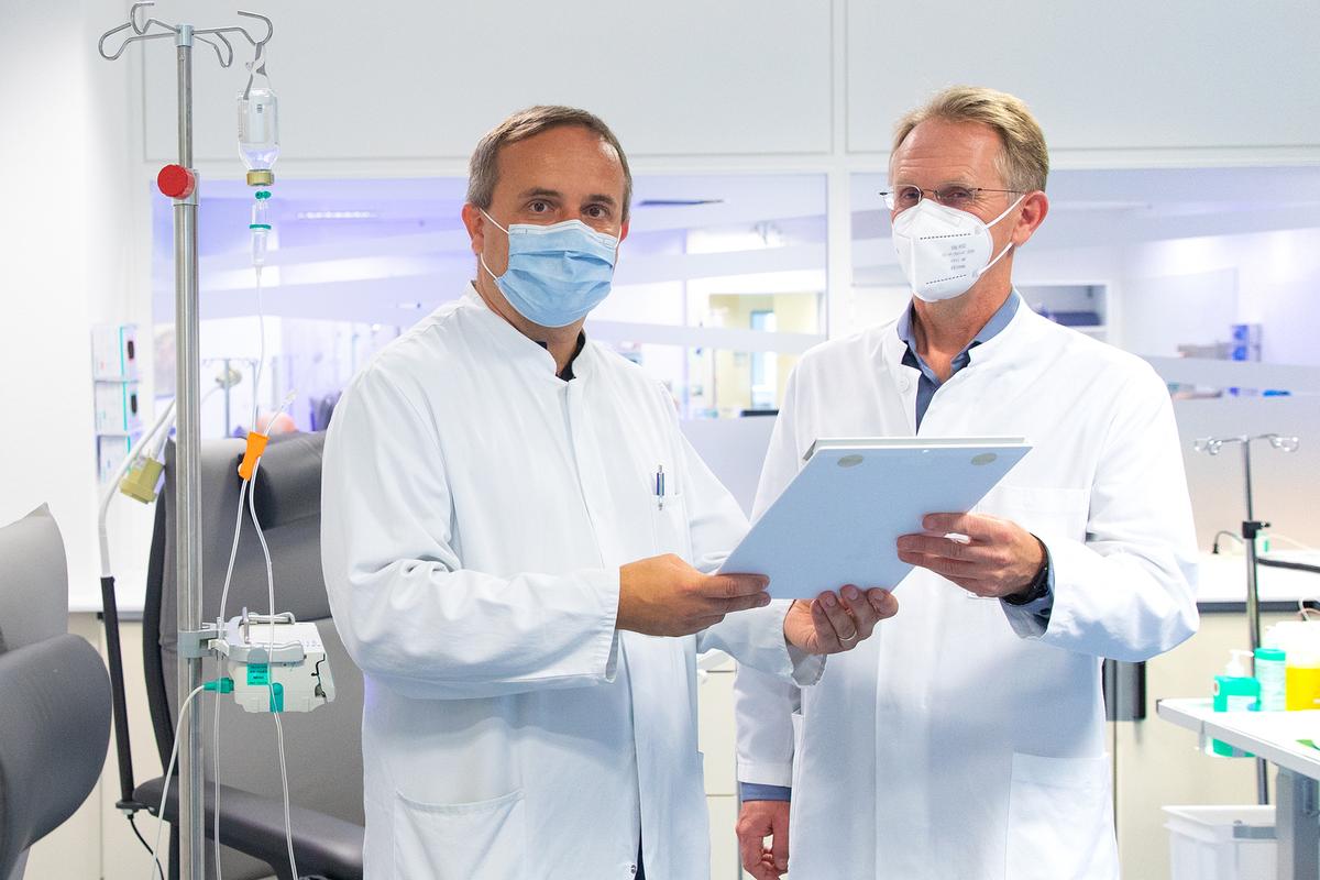   Two doctors stand in a treatment room for amyloidosis patients and discuss.