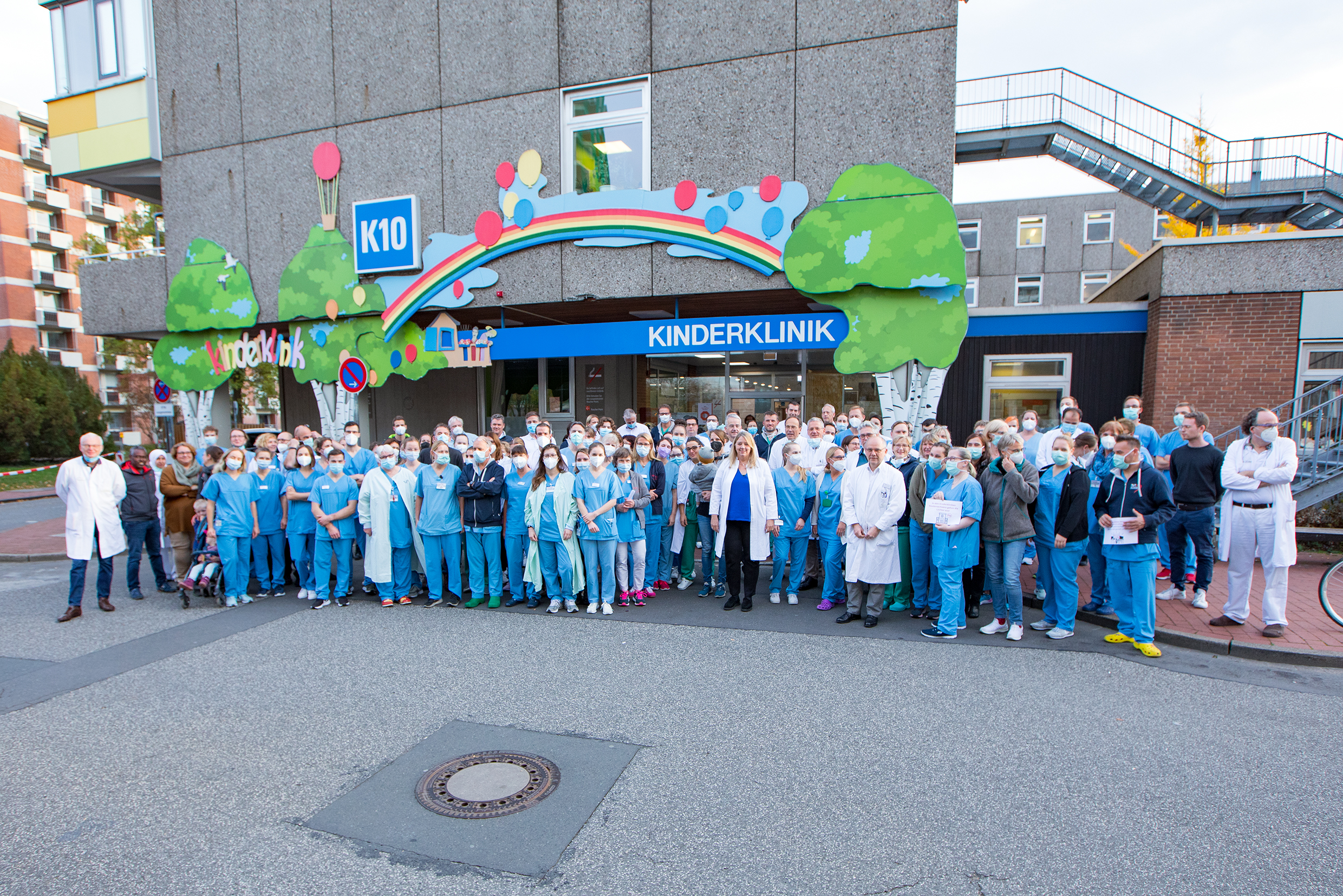 Beschäftige stehen vor dem Gebäude der MHH-Kinderklinik