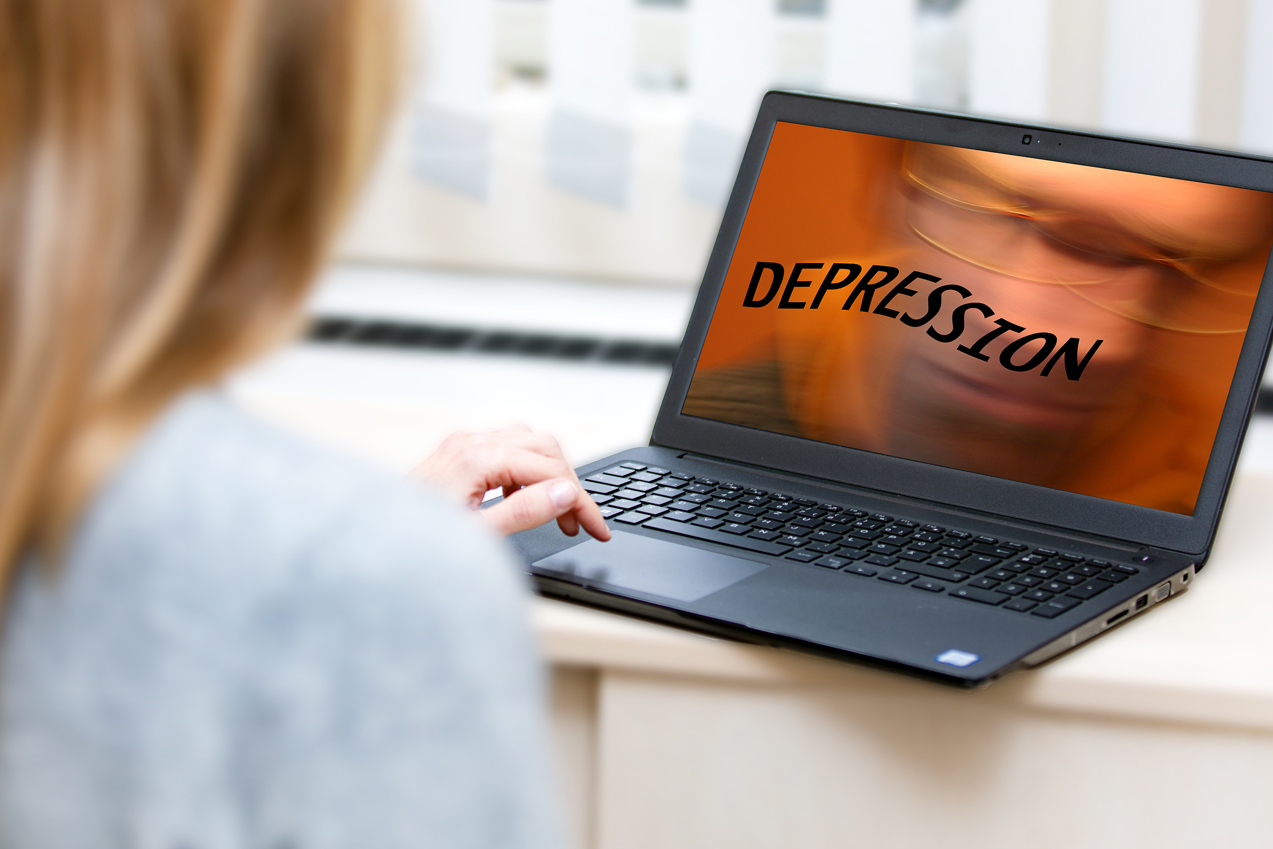 Eine Person sieht auf einen Bildschirm, auf dem groß das Wort „Depression“ erscheint.