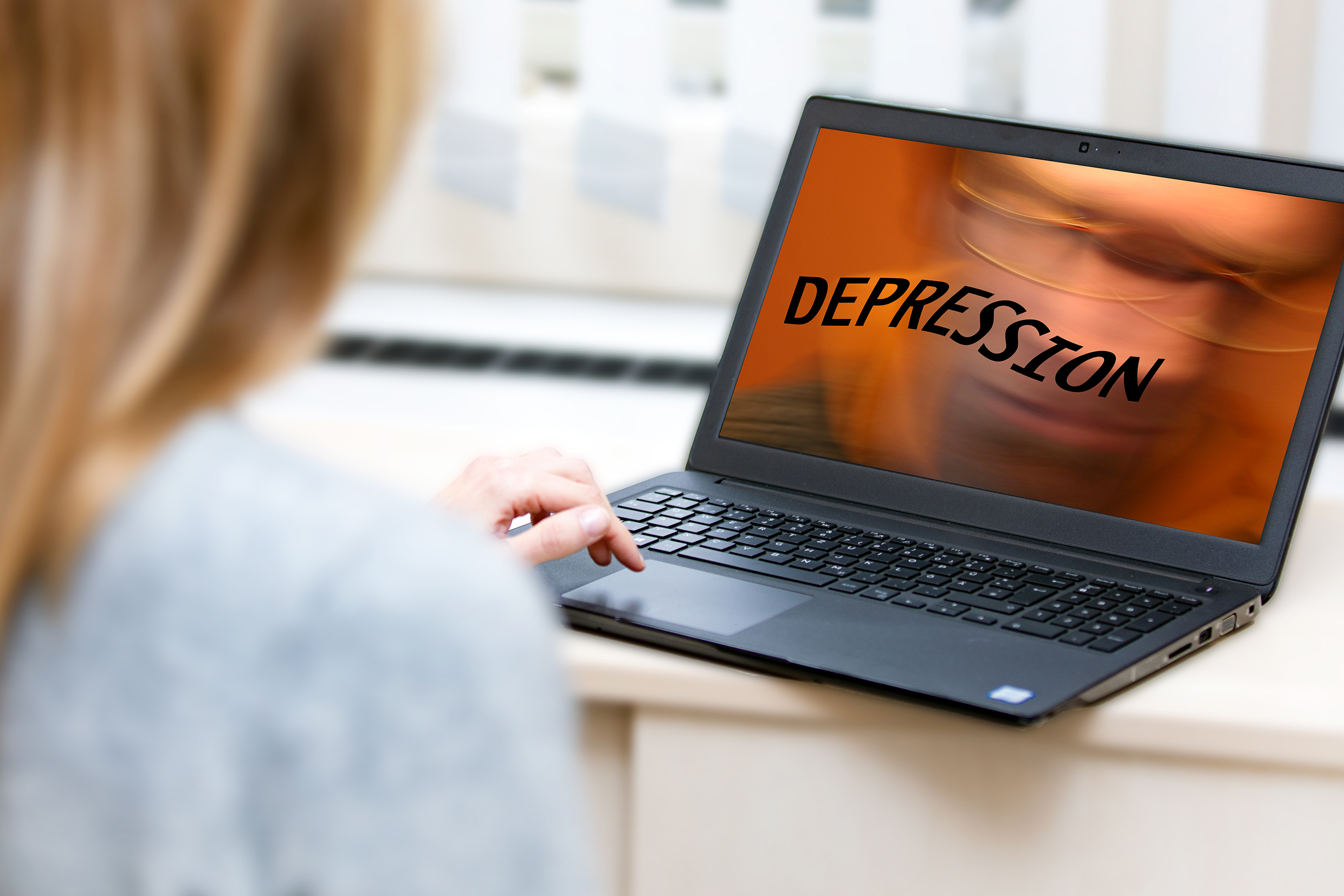 A person looks at a screen on which the word "depression" appears in large letters.