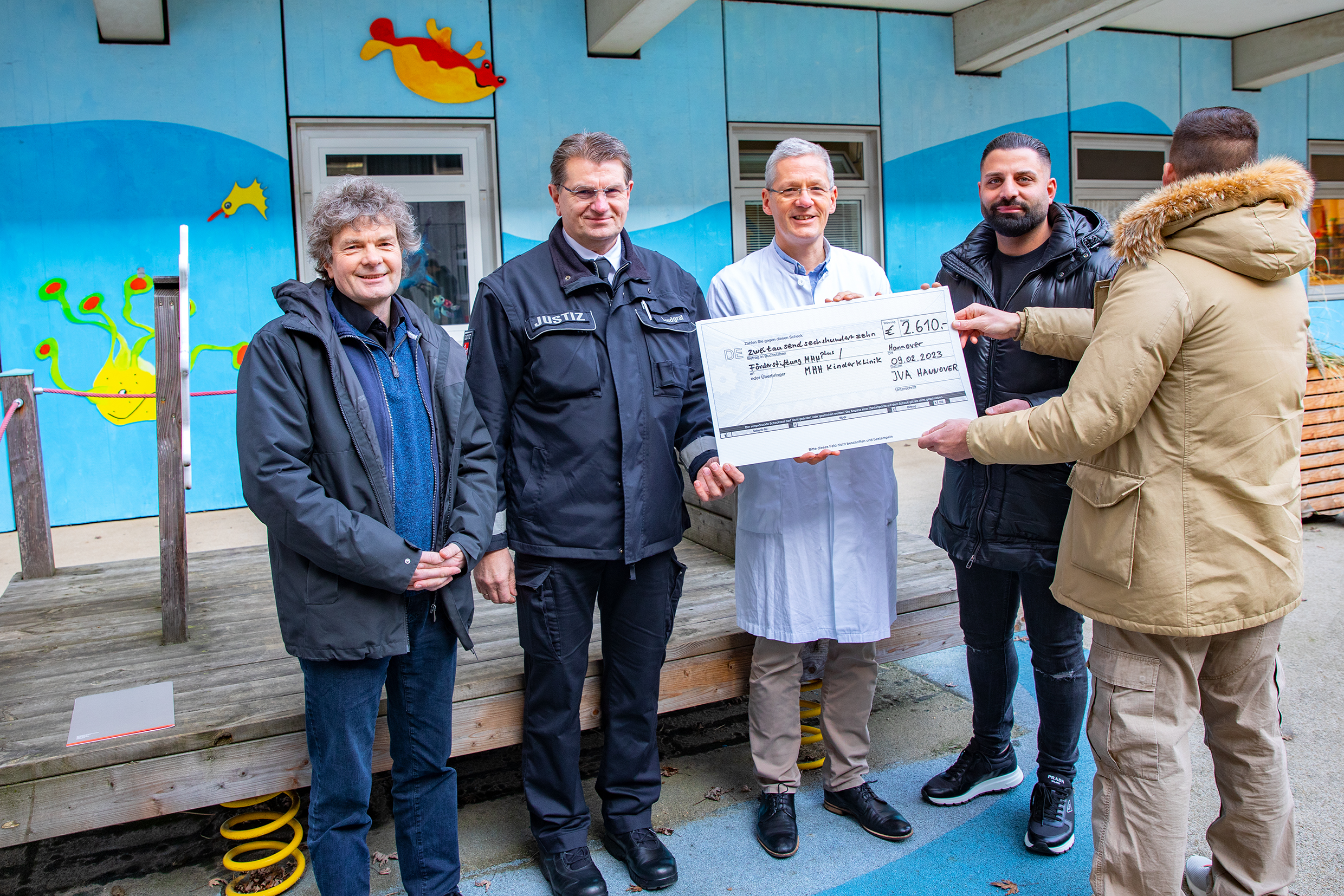 V.l.n.r.: Dr. Eckhard Schenke (MHH plus), Peter Landgraf (JVA Hannover), Prof. Dr. Philipp Beerbaum (MHH), Volkan Gül (Spender) und Alexander A. halten im Innenhof der MHH Kinderklinik einen symbolischen Check. Copyright: Karin Kaiser / MHH. 