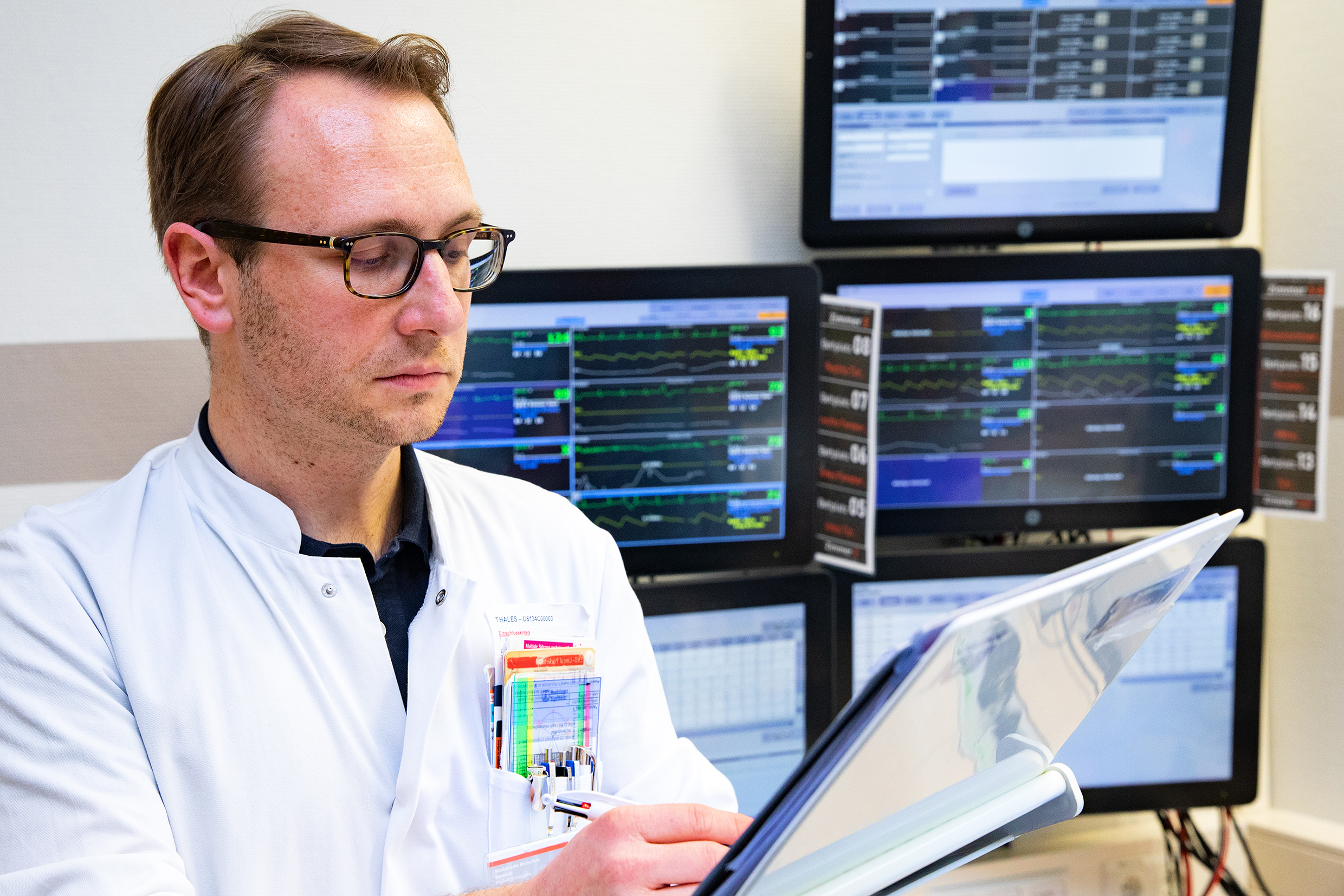 PD Dr. Gerrit Große holds a file in his hand and looks at clinical data of stroke patients on the stroke unit.