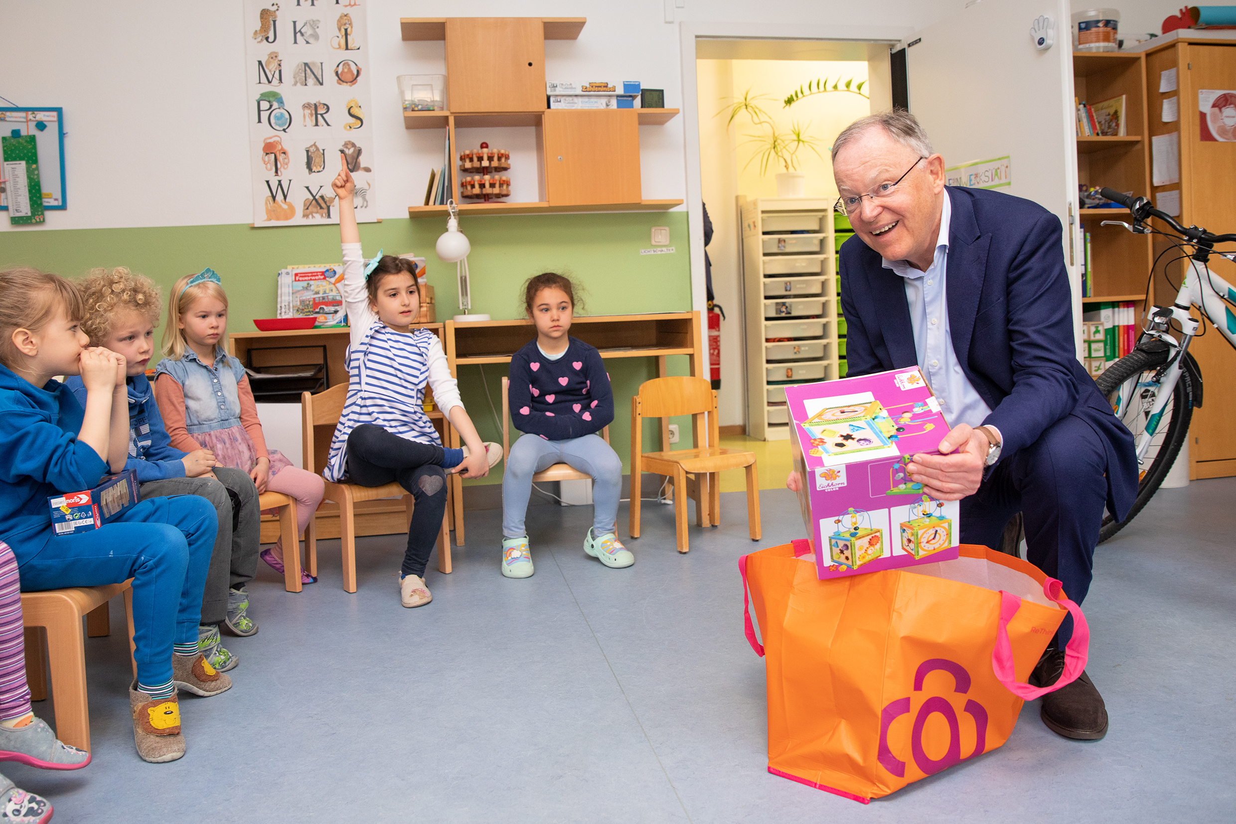 Der Niedersächsische Ministerpräsident Stephan Weil hat bei seinem Besuch in der MHH-Kita Campuskinder Spielzeuggeschenke mitgebracht und übergibt sie den Kindern.