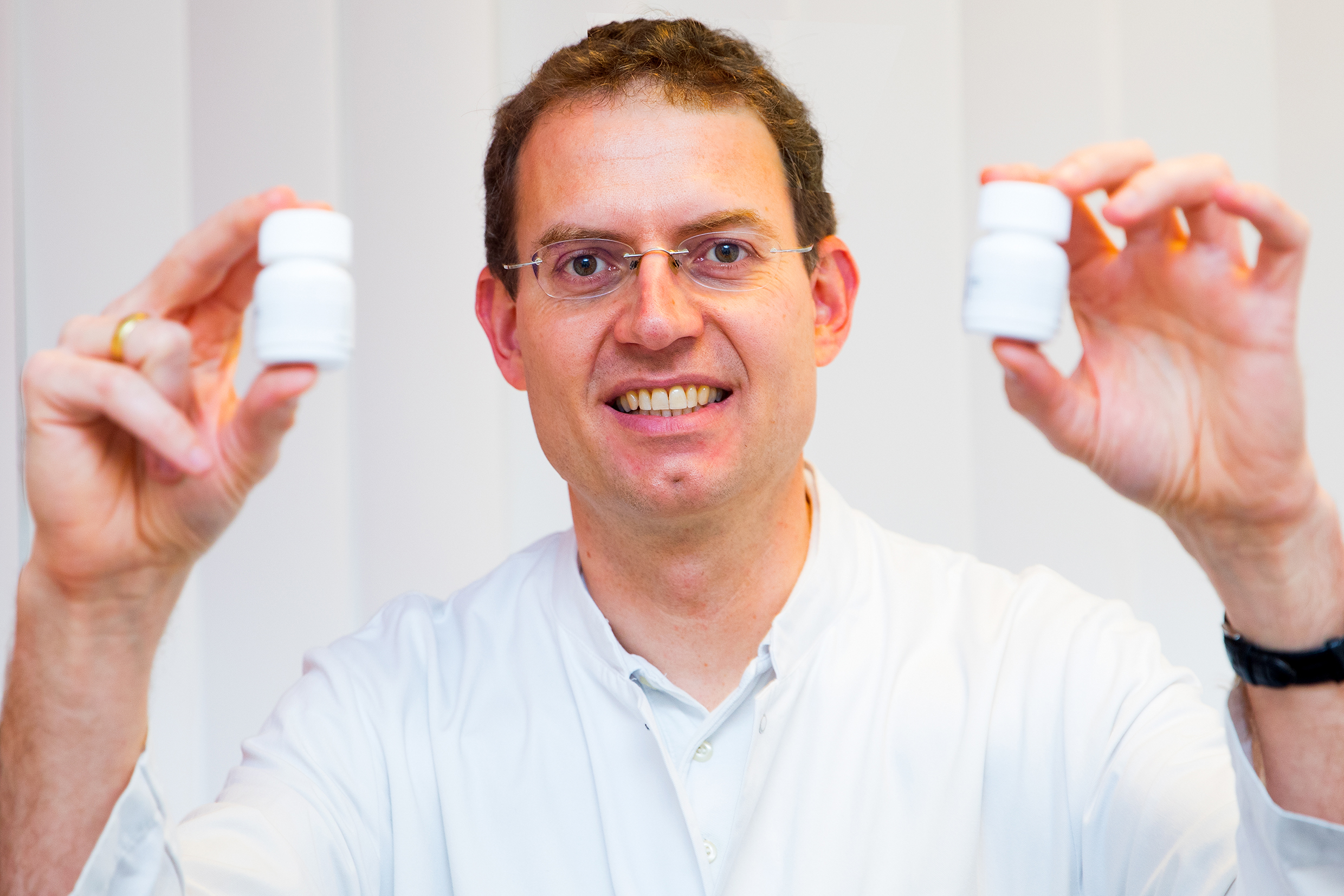 Professor Dr. Michael Heuser holds two drug containers in his hands