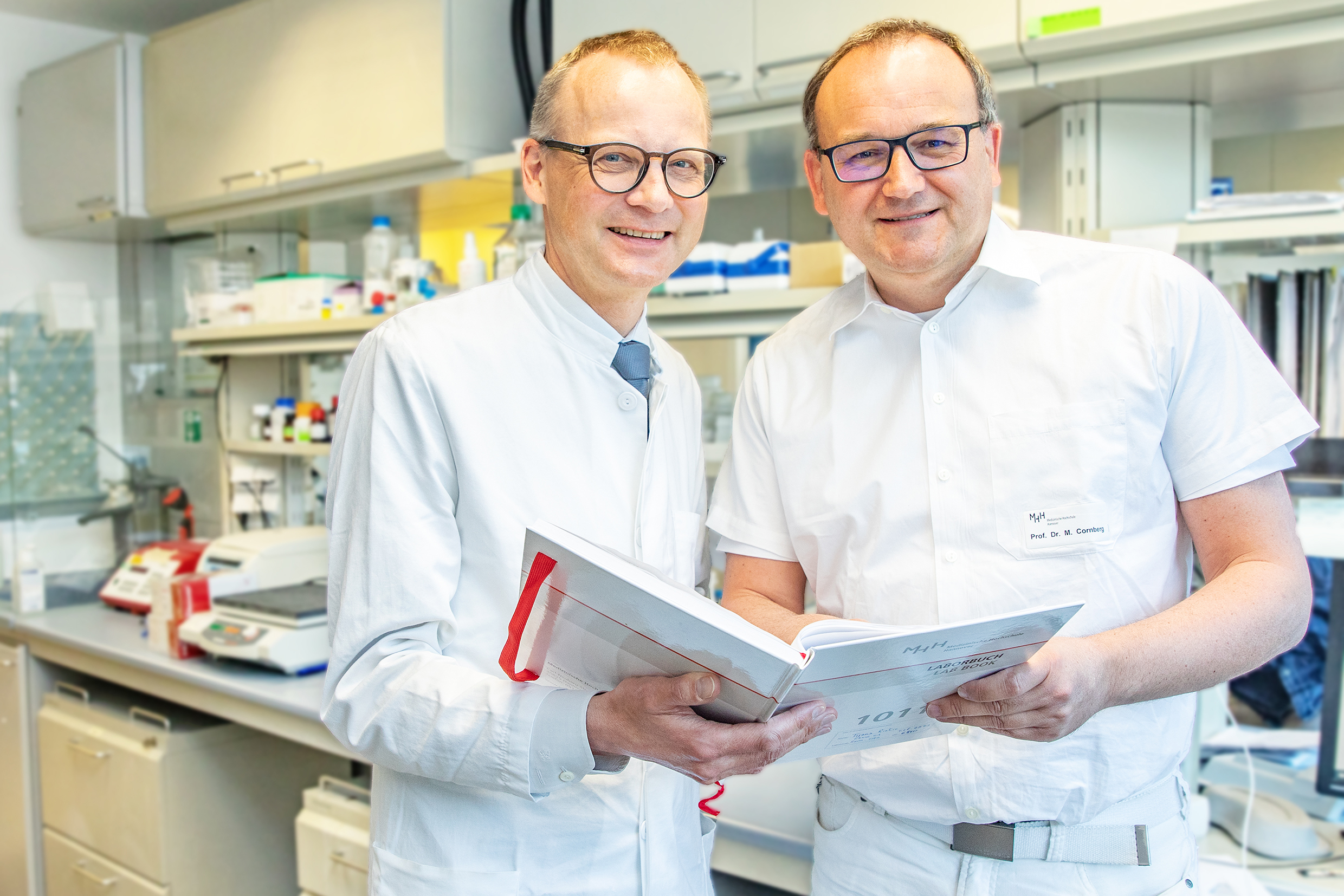 Professor Dr. Heiner Wedemeyer (links) und Professor Dr. Markus Cornberg stehen in einem Labor der Klinik für Gastroenterologie, Hepatologie, Infektiologie und Endokrinologie.