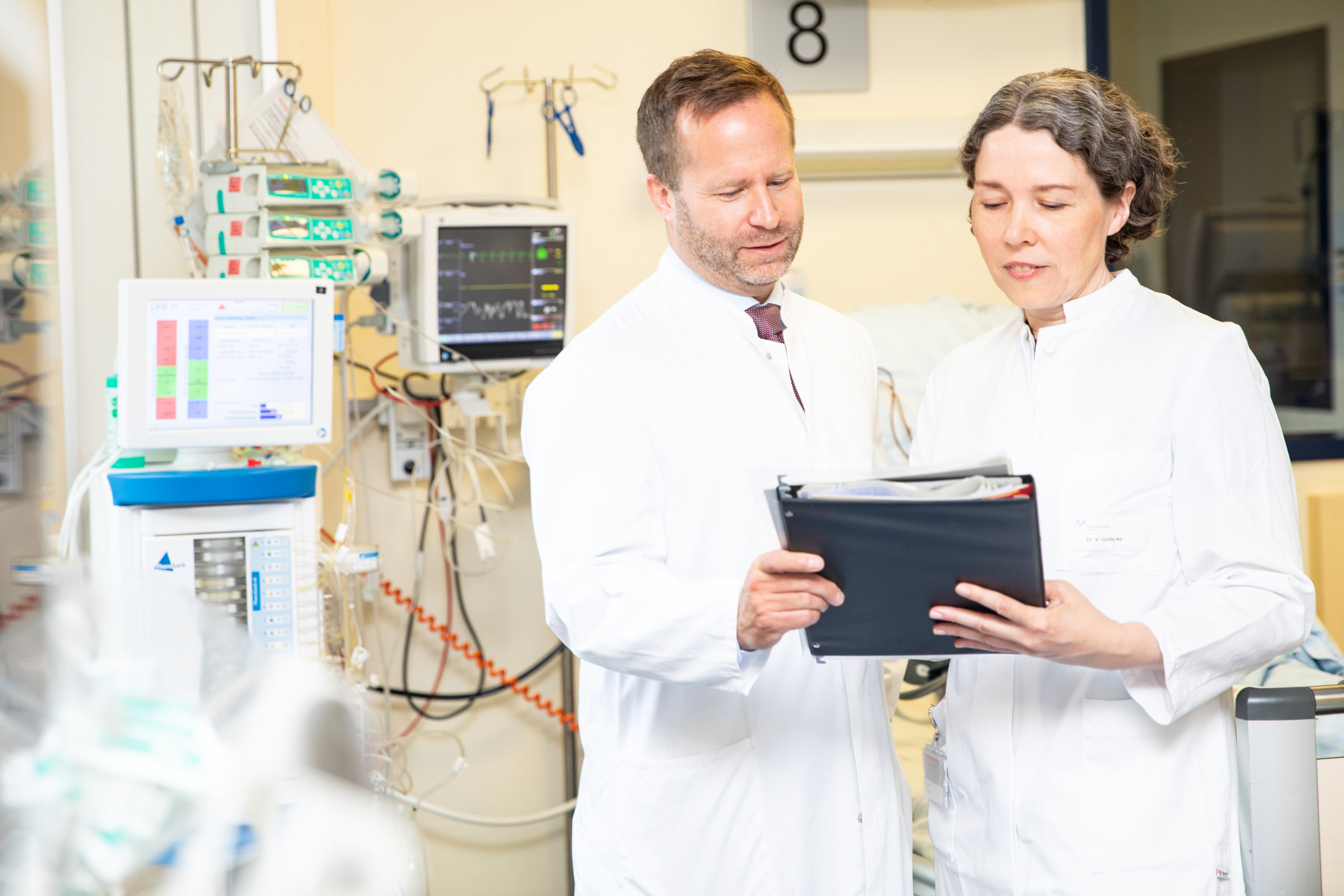 Professor Dr. Kai Schmidt-Ott und Dr. Vega Gödecke stehen in einem Zimmer der Dialysestation der Klinik für Nieren- und Hochdruckerkrankungen und betrachten eine Patientenakte.