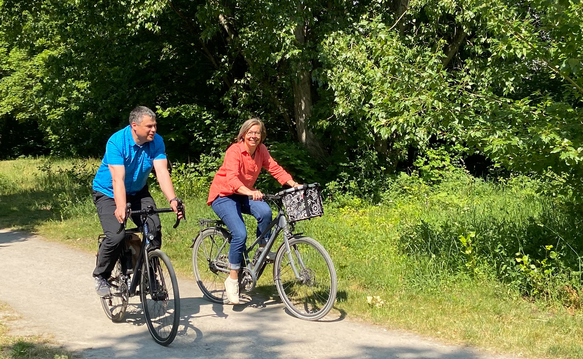 two persons on bikes riding through a green park