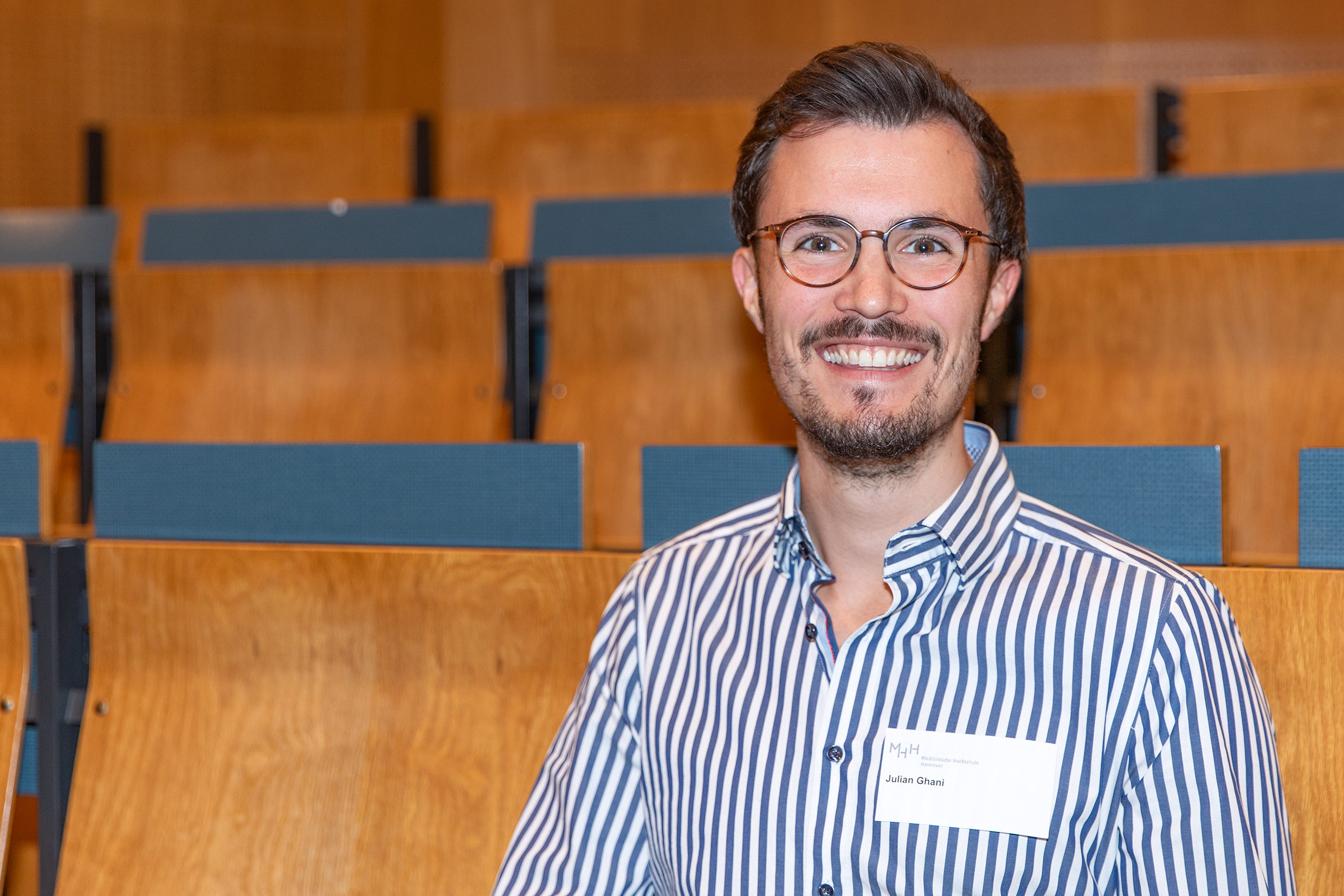 Julian Ghani sitzt in einem Hörsaal. Er ist Berufsmusiker und Medizinstudent.