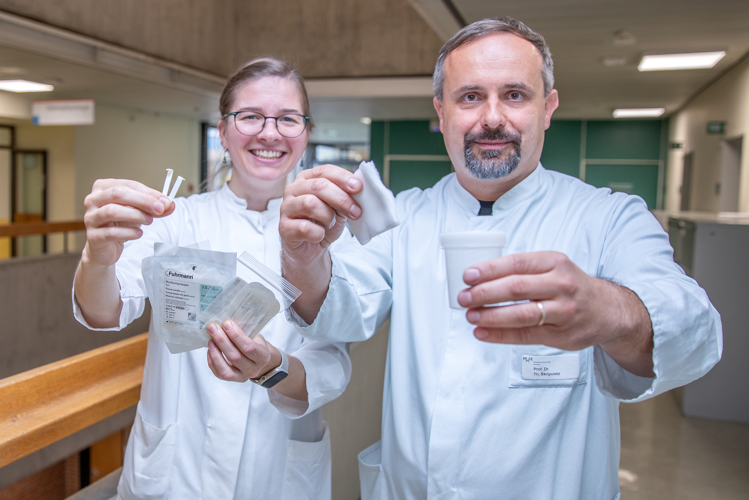 Eine Ärztin und ein Arzt stehen in der Klinik für Neurologie und halten Schirmer-Tests und Mullbinden für die Sjögren-Diagnose in den Händen. 