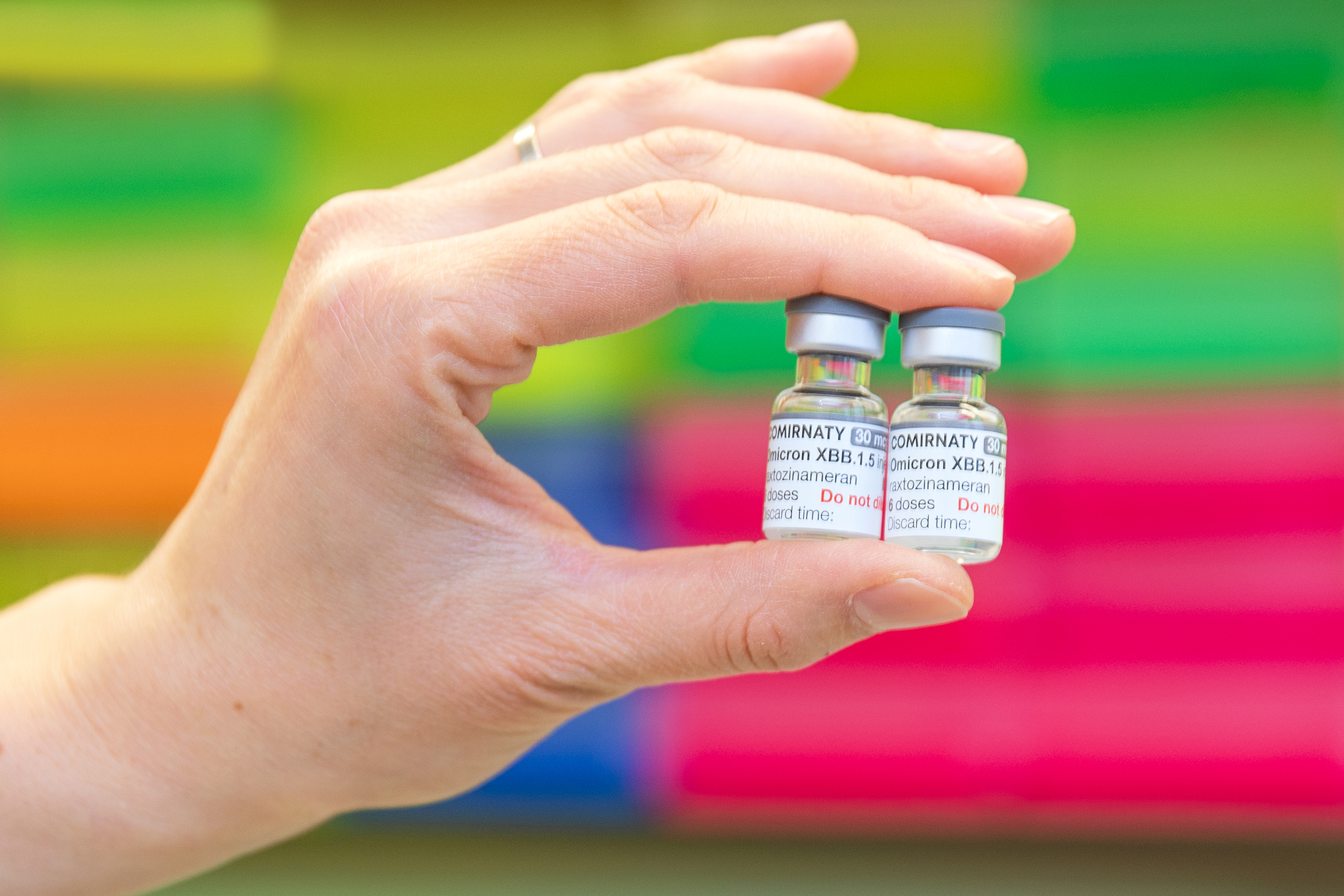 One hand holds two vials of coronavirus vaccine.