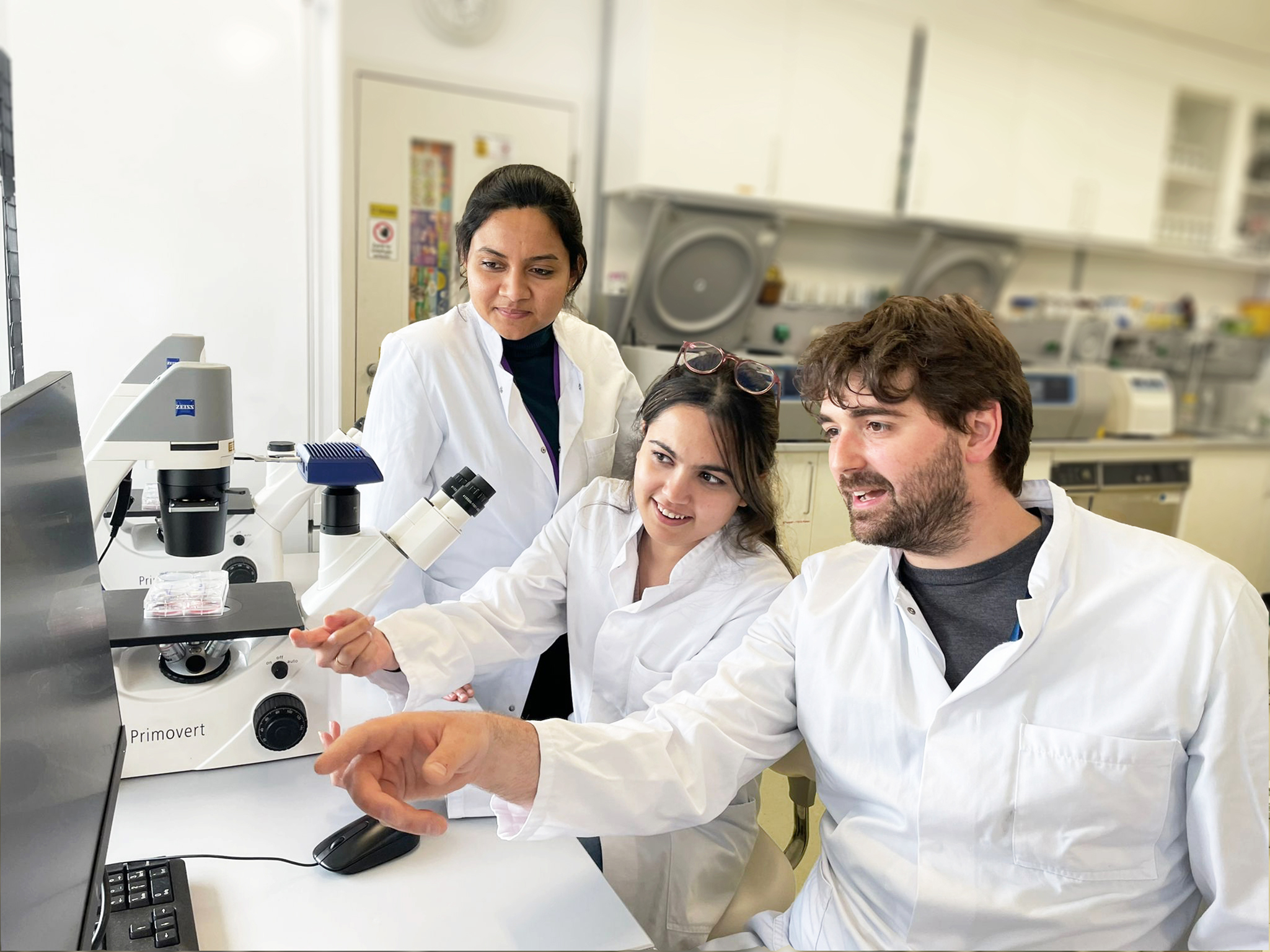 Dr Florian Perner sits in a laboratory with two employees.