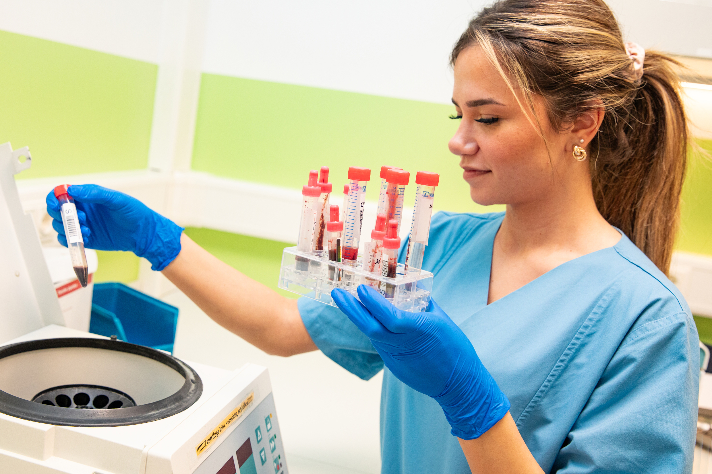 Eine junge Frau hält ein Röhrchen mit einer Blutprobe in der Hand. 